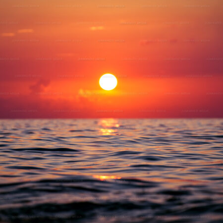 Crimson sun setting over deep ocean water in The Bahamas.