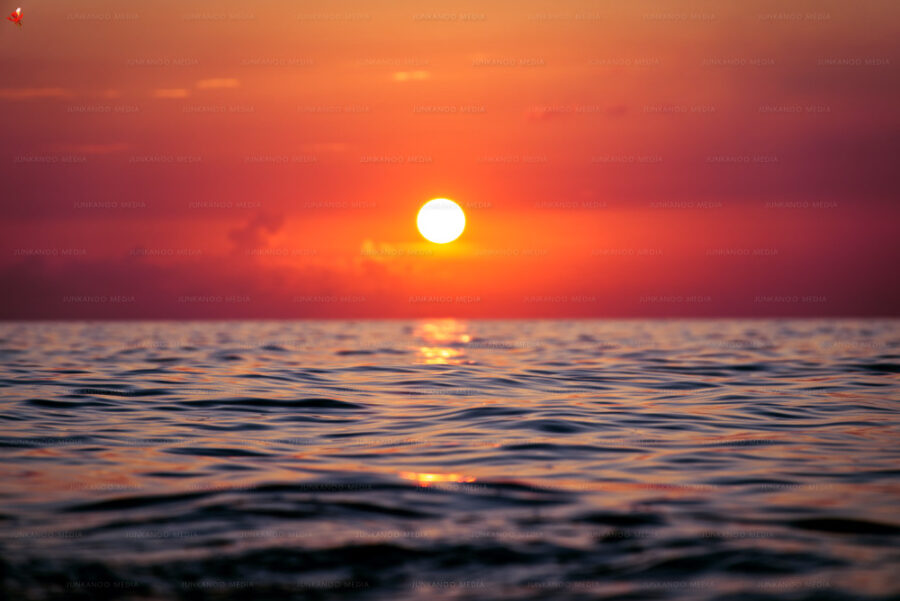 Crimson sun setting over deep ocean water in The Bahamas.