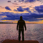 A man stands lookout at the eastern Nassau harbor entrance beneath low lying clouds.