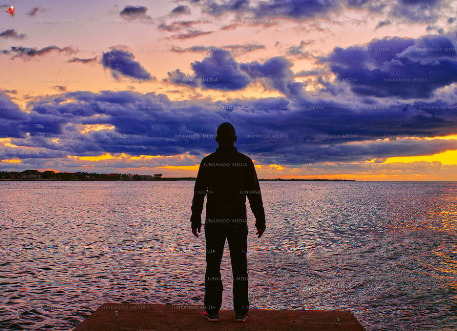 A man stands lookout at the eastern Nassau harbor entrance beneath low lying clouds.