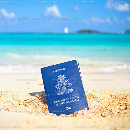 Bahamian passport in the sand on Junkanoo Beach with Nassau lighthouse in the background.