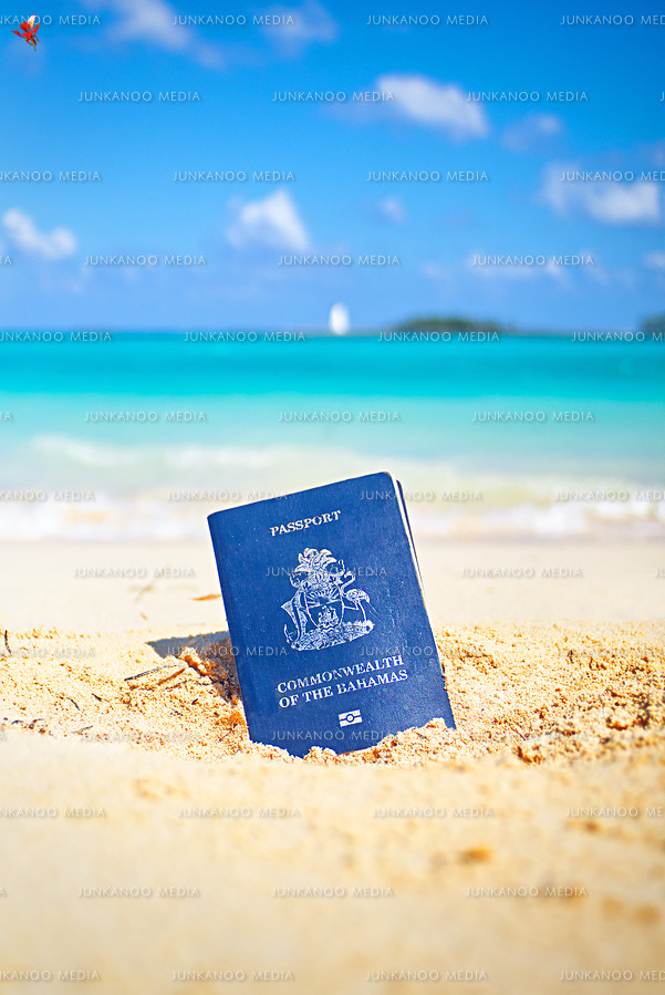 Bahamian passport in the sand on Junkanoo Beach with Nassau lighthouse in the background.