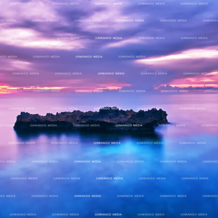 A long exposure of a rock formation sitting in the ocean.
