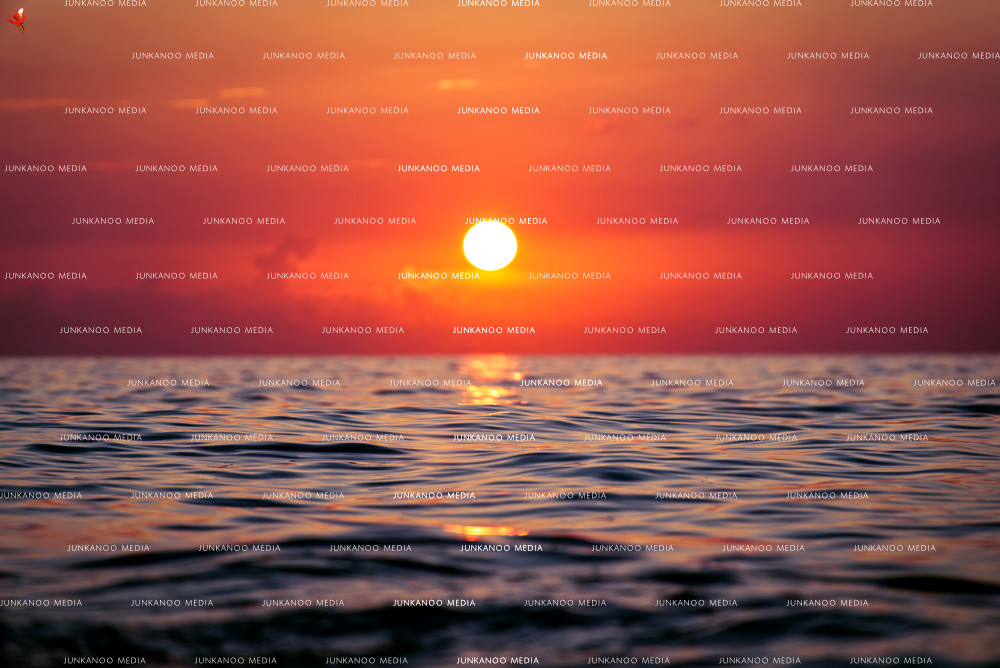 Crimson sun setting over deep ocean water in The Bahamas.