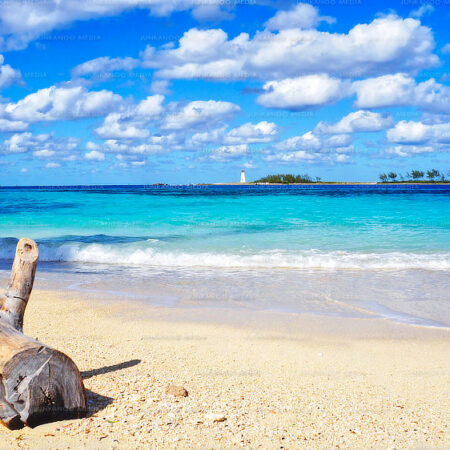 A beach in The Bahamas with white puffy clouds floating above.