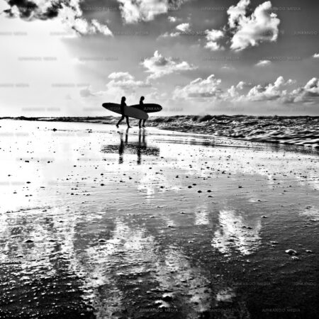 Two young women take their surfboards into the rough sea at Old Fort Bay, Nassau, Bahamas.