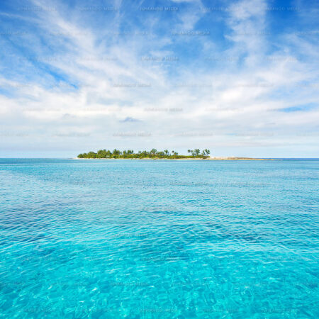 A Bahamian island sits in calm water surrounded by stratus cloud formation.