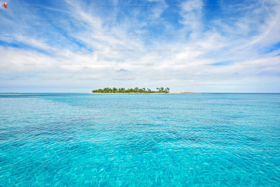 A Bahamian island sits in calm water surrounded by stratus cloud formation.