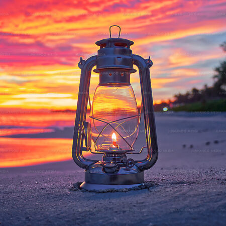 Lantern on Cabbage Beach sitting on sand with ocean and morning sunrise in background.