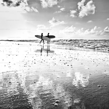 Two women take their surfboards into the rough sea at Old Fort Bay, Nassau, Bahamas.