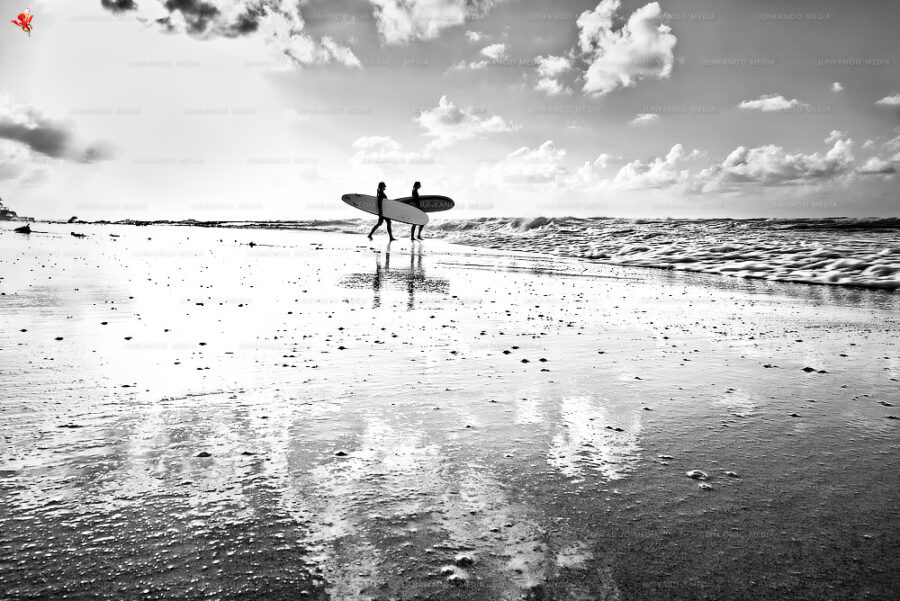 Two women take their surfboards into the rough sea at Old Fort Bay, Nassau, Bahamas.