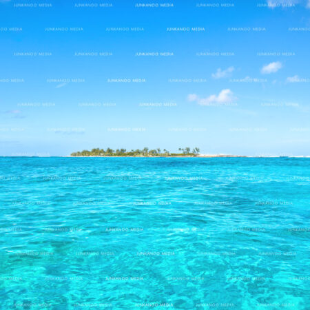 Daylight shot off an island in The Bahamas surrounded by turquoise waters and vibrant blue sky.