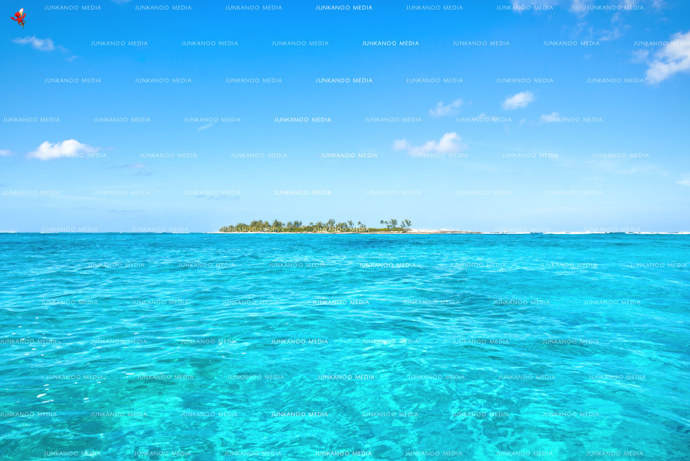 Daylight shot off an island in The Bahamas surrounded by turquoise waters and vibrant blue sky.