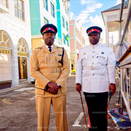 Two police officers, one wearing khaki colonial dress and the other wearing black pants with a red stripe and ceremonial white dress shirt in Nassau, Bahamas.