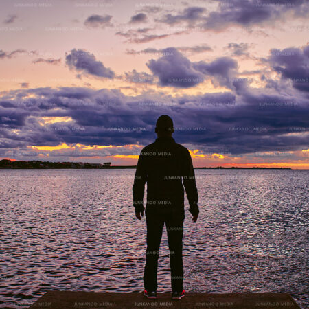 A man stands lookout at the eastern Nassau harbor entrance beneath low lying clouds.