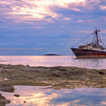 Bahamian fishermen try their luck at sunset, across from trawler "Adrianna" with Balmoral Island in the background.